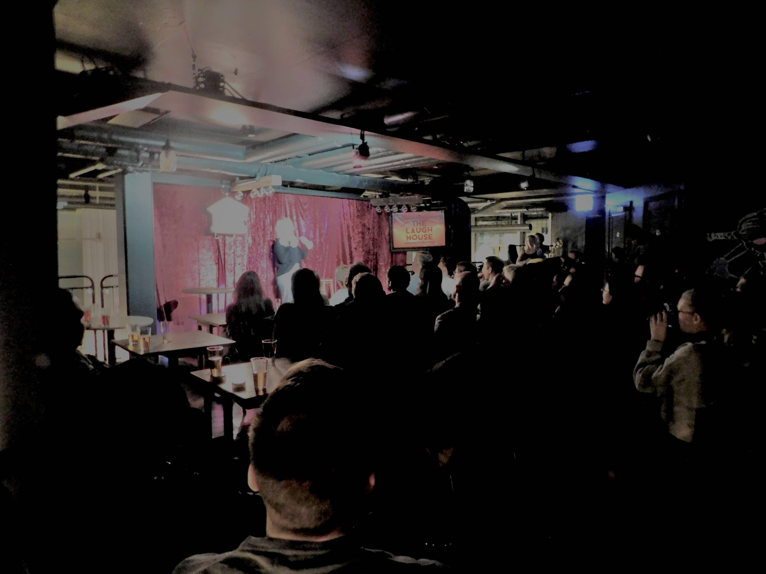 A full audience watching a comedian perform at The Laugh House